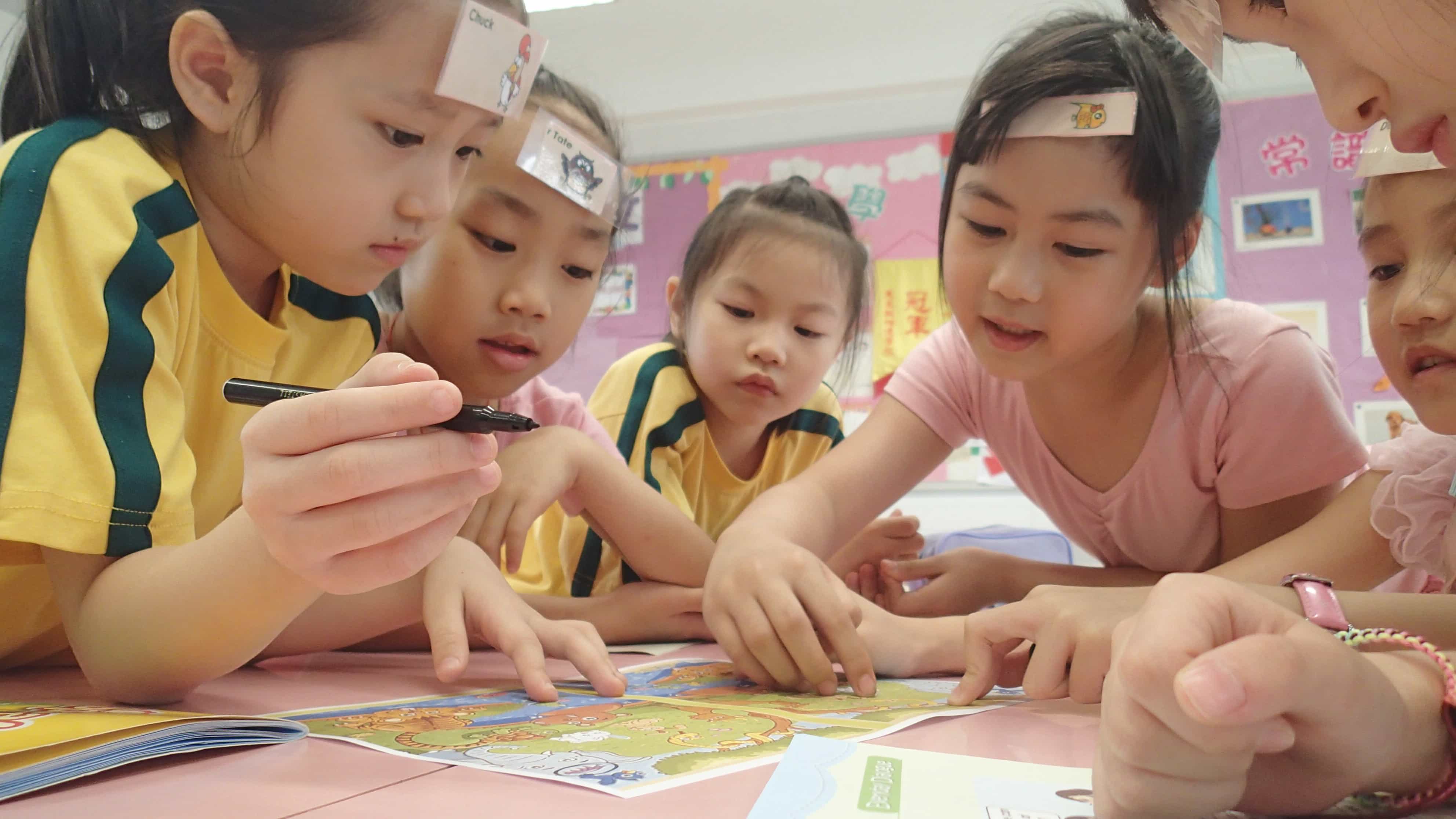 asian school girls are playing a table game in a TEFL classrom